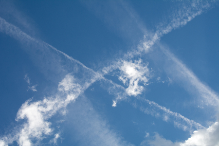 Vapour trails from planes crossing a blue skyの写真素材
