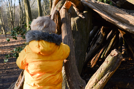 Young boy playing outside learning to build a den in the forestの写真素材