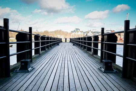 Wooden pier in a peaceful scene overlooking a city riverの写真素材