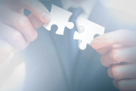 Business solutions. business man holds two pieces of puzzle togetherの写真素材