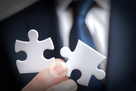 Business solutions and strategy concept of business man holding connecting pieces of puzzleの写真素材