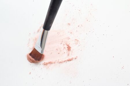 Make up brush on white surface, cosmetic makeup powder exploding as it impacts tableの写真素材