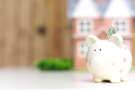 Piggy bank and new home, concept of saving money to pay for mortgage of new propertyの写真素材