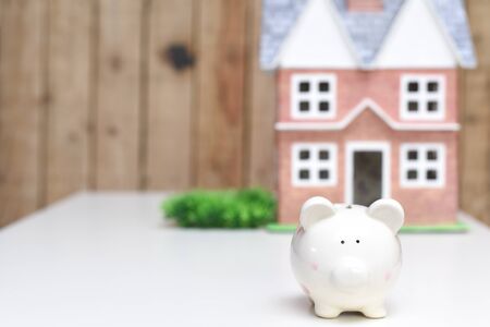 Piggy bank and new home, concept of saving money to pay for mortgage of new propertyの写真素材