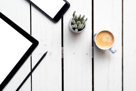 Office objects, devices with blank screens. White screen on smartphone and tablet on wooden table
