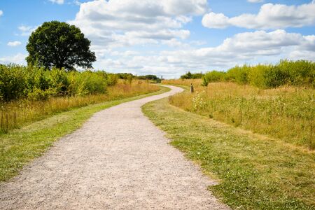 Long winding gravel footpath through a country field No people. view to horizonの写真素材