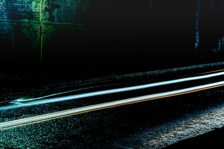 Light trails from cars passing through a dark tunnel on a rainy nightの写真素材