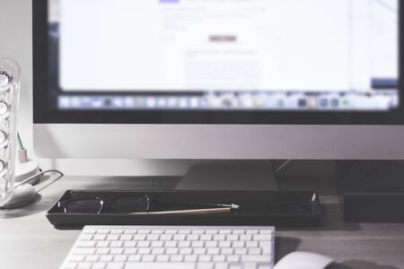 Blurred large computer screen on a home office desk interior eith work objects in backgroundの写真素材