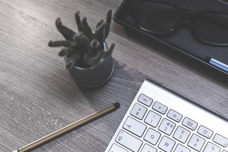 Modern office desk overhead in home office with computer keyboard and office objects on wooden deskの写真素材