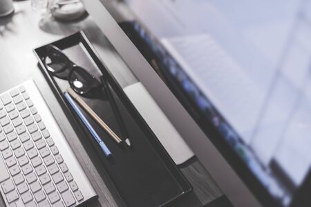 Blurred large computer screen on a home office desk interior eith work objects in backgroundの写真素材