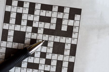 Crossword puzzle from newspaper with a pen to fill in answersの写真素材