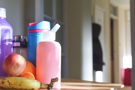Group of water bottles and healthy fruit snack for the family on a kitchen table in the morningの写真素材