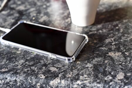 Phone plugged in to charging with charging cable in domestic home kitchen