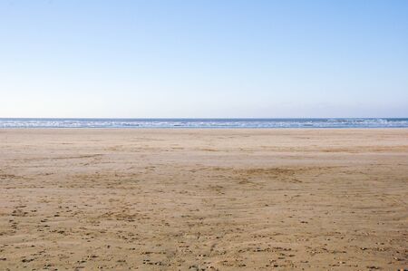 Large empty sandy beach with golden sand leading to the oceanの写真素材