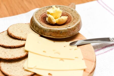 Cheese and biscuits snack of oat cakes with butter and emmental cheese on a board