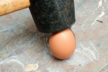 Egg being smashed or cracked with a hammerの写真素材