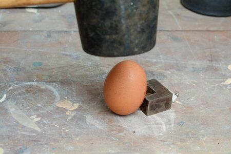 Egg being smashed or cracked with a hammerの写真素材