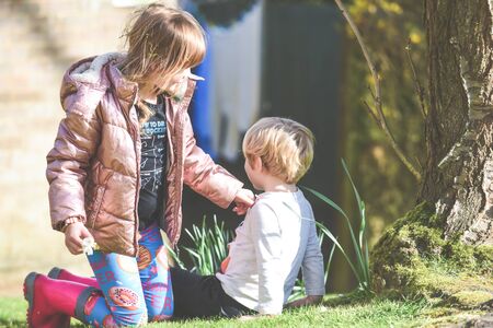 Siblings playing together a boy and girl are playing outside in a garden during daytimeの写真素材