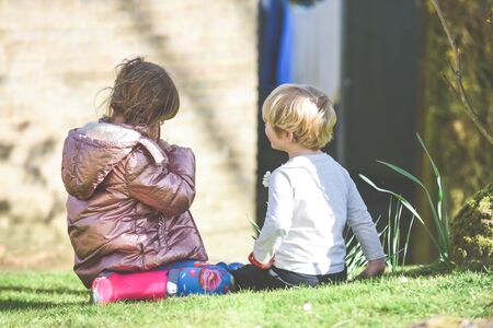 Siblings playing together a boy and girl are playing outside in a garden during daytimeの写真素材