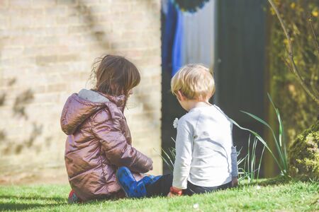 Siblings playing together a boy and girl are playing outside in a garden during daytimeの写真素材