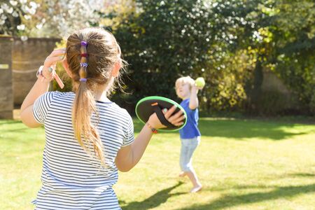 Children playing outside a brother and sister play a ball game in a gardenの写真素材