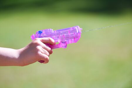 Pink water gun shooting water close up in a gardenの写真素材