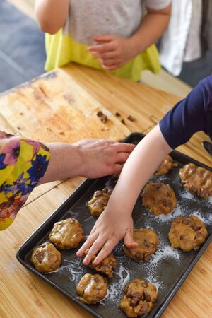 Kids making cookies in kitchen placing dough on tray for cooking at homeの写真素材
