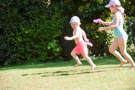Kids playing with water in a garden on a sunny summer dayの写真素材