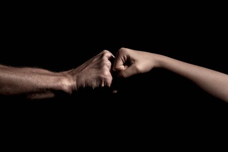 two hands fist bump together over black backgroundの写真素材