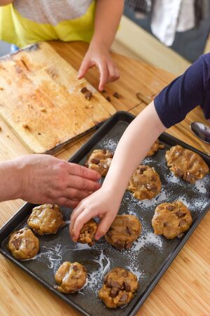 Kids making cookies in kitchen placing dough on tray for cooking at homeの写真素材