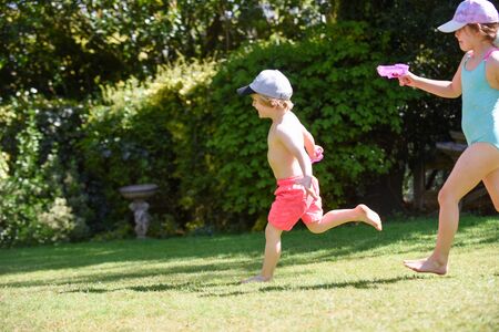 Kids playing with water in a garden on a sunny summer dayの写真素材