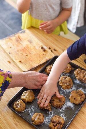 Kids making cookies in kitchen placing dough on tray for cooking at homeの写真素材