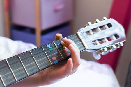 A girl learns to play guitar at home close up on handsの写真素材