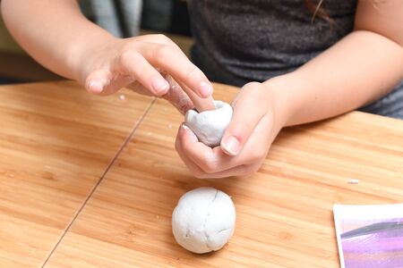 Girl making pottery models with white clay at homeの写真素材