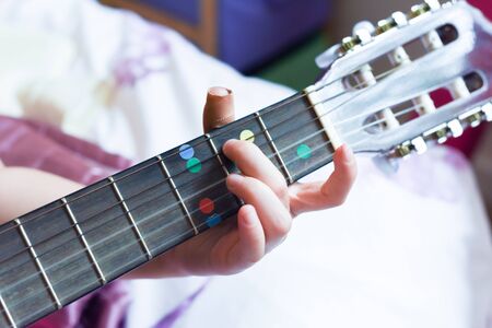 A girl learns to play guitar at home close up on handsの写真素材