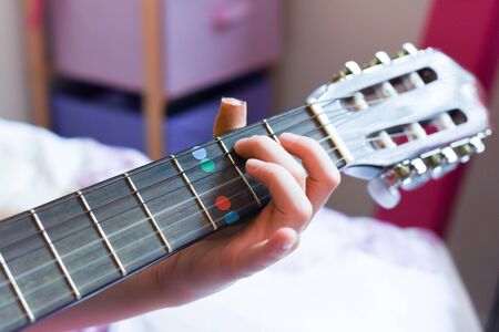 A girl learns to play guitar at home close up on handsの写真素材