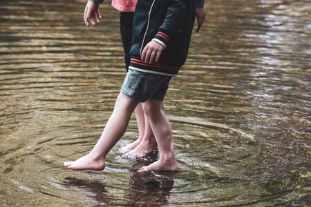 Children playing together in water outside in a stream during a warm dayの写真素材