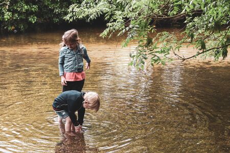 Children playing outside in a shallow stream paddling in the waterの写真素材