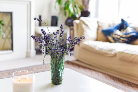 Modern home interior of living room with scented candle and lavender flowers on coffee tableの写真素材