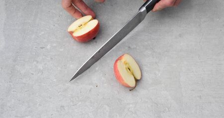 Cutting an apple fresh fruit preperation inside a kitchen on a chopping boardの写真素材