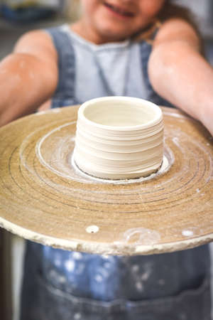 Child holds up a bowl made during ceramic pottery making classの写真素材