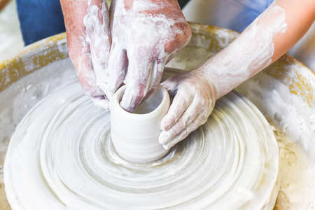 Children learning to make pottery as a hobby with their grandmother in a ceramics workshopの写真素材