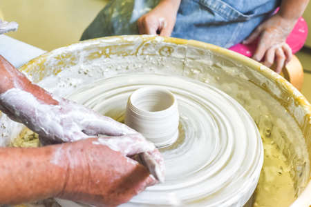 Children learning to make pottery as a hobby with their grandmother in a ceramics workshop