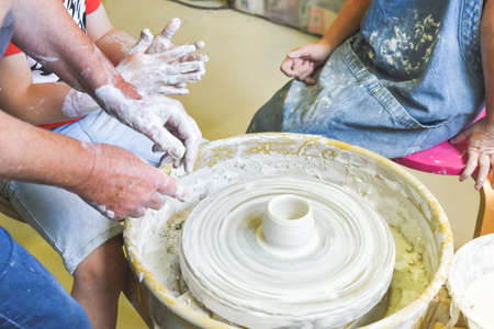 Children learning to make pottery as a hobby with their grandmother in a ceramics workshopの写真素材