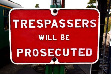 old fashioned trespassers will be prosecuted red metal sign with white painted letters.の写真素材