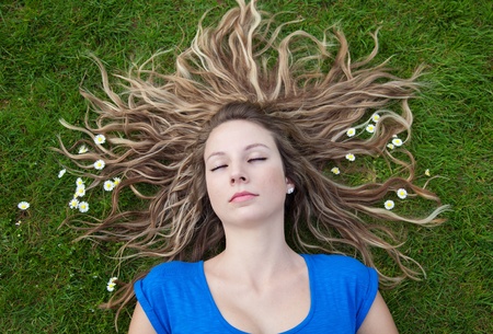 Sleeping beauty with her hair spread out on grassの写真素材