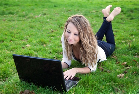 Young beautiful woman in park with laptop の写真素材