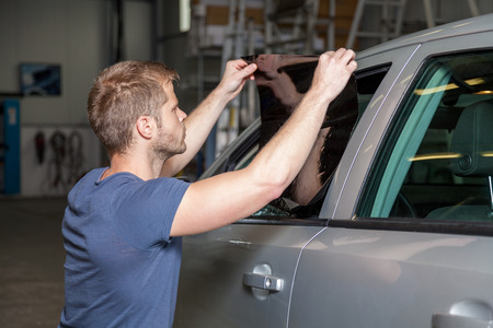 Applying tinting foil onto a car window in a workshopの写真素材