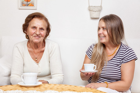 Carer having a cup of tea with an elderly retired womanの写真素材