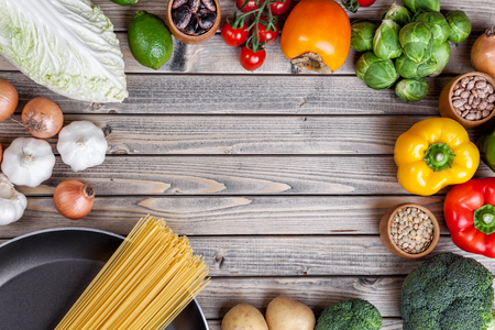 Various vegetables fruits and herbs with a frying pan on wooden backgroundの写真素材